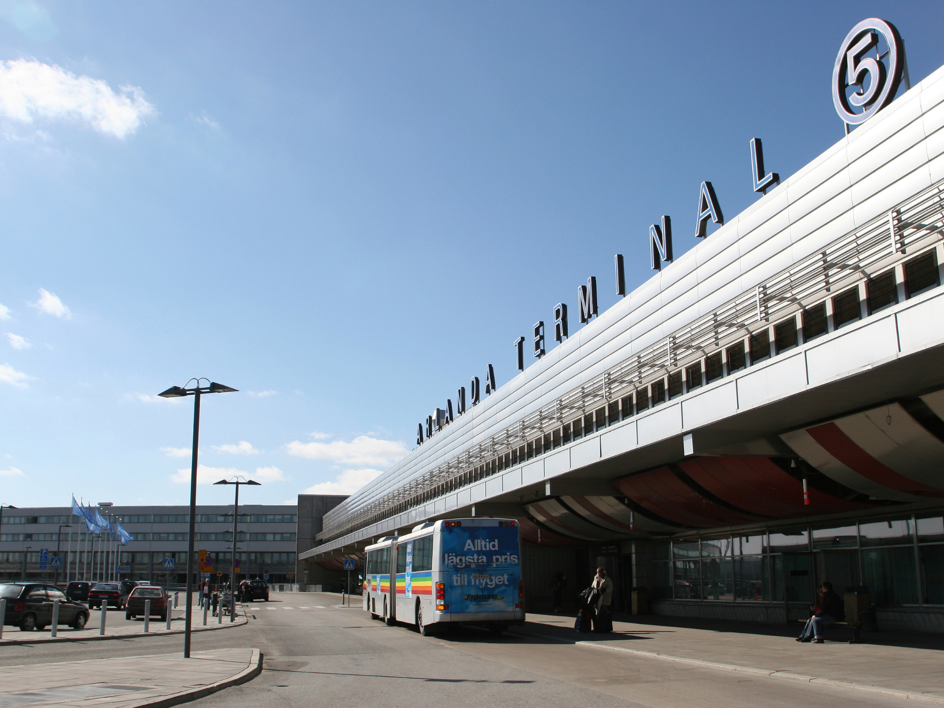 Exteriör av Arlanda flygplatsterminal med glasfasad och skyltar, ett viktigt landmärke nära tunneln.