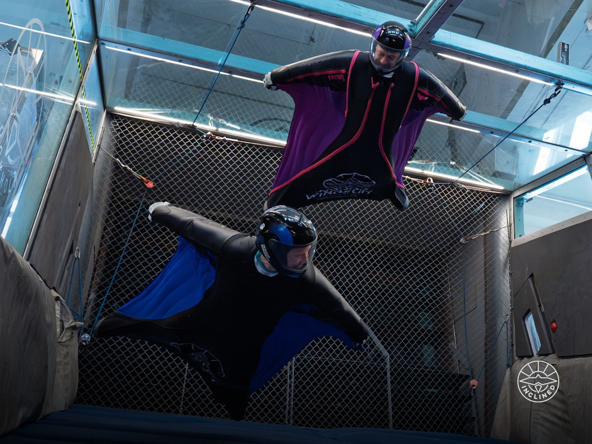 Two wingsuit flyers soar in tunnel built by Indoor Wingsuit tech inventors for authentic flight.