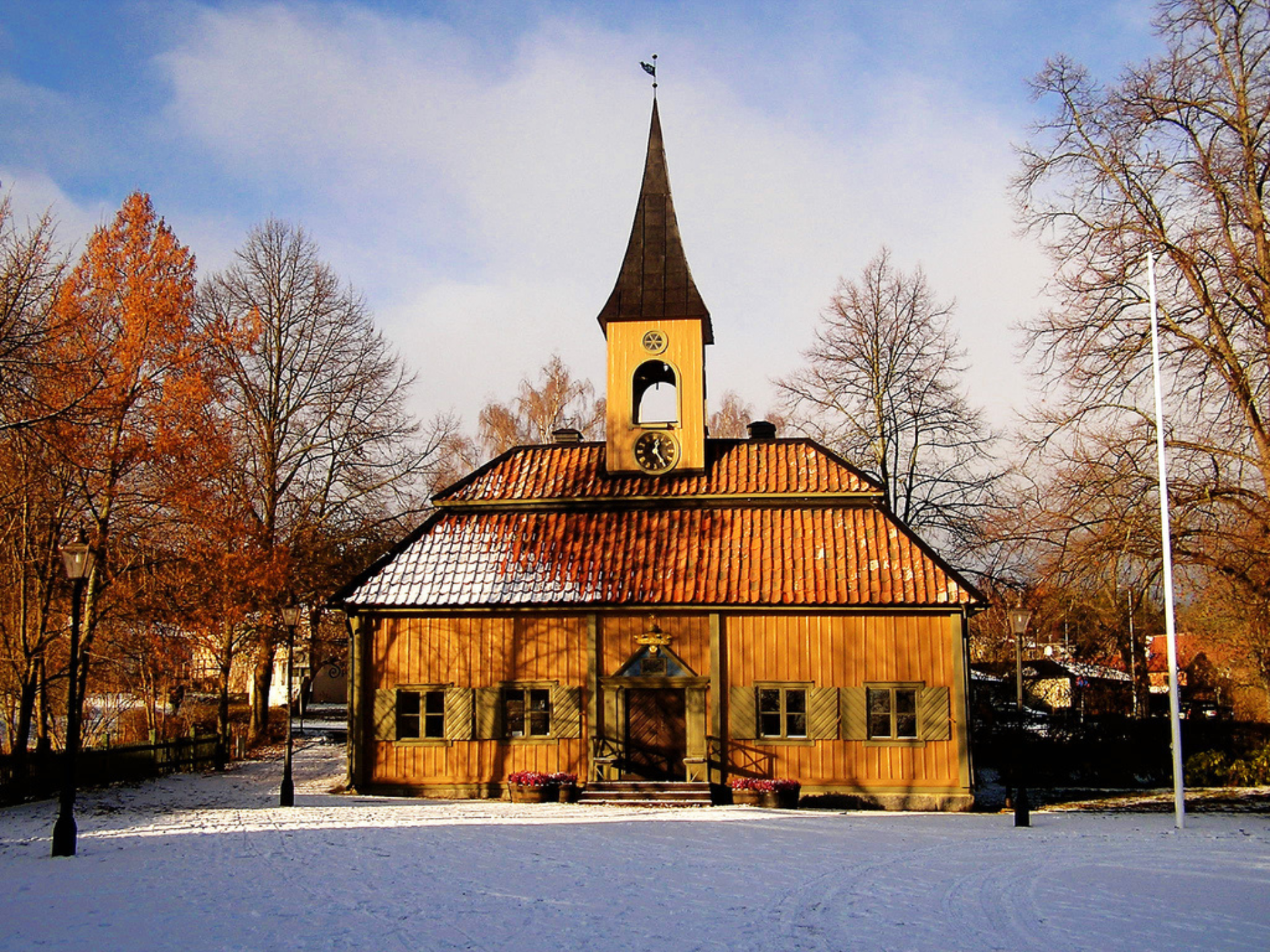 Träkyrka med högt torn och snötäckt mark, en del av Sveriges äldsta stad nära tunneln.