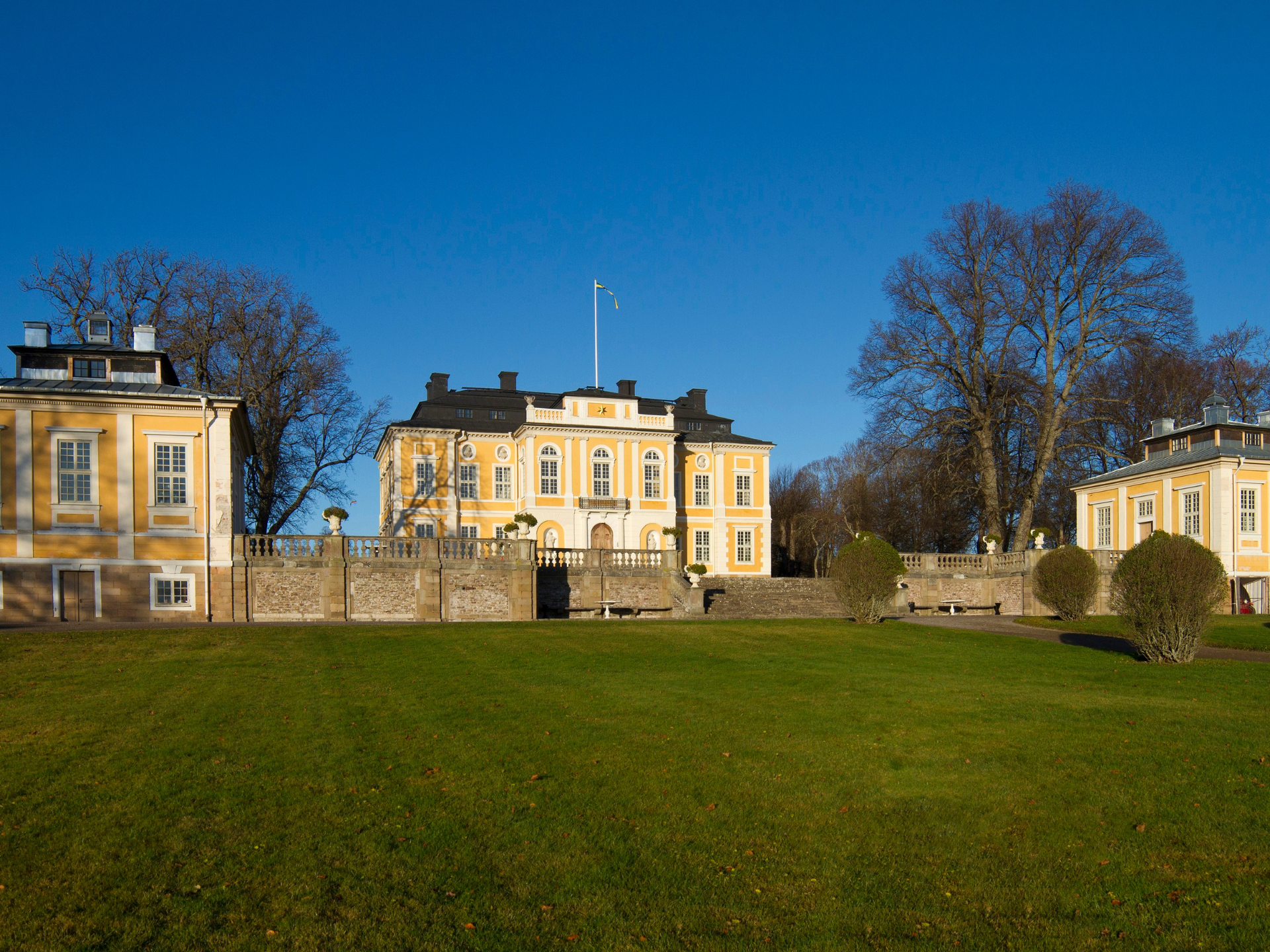 Historiskt gult slott med grön gräsmatta och träd, en populär attraktion nära tunneln.